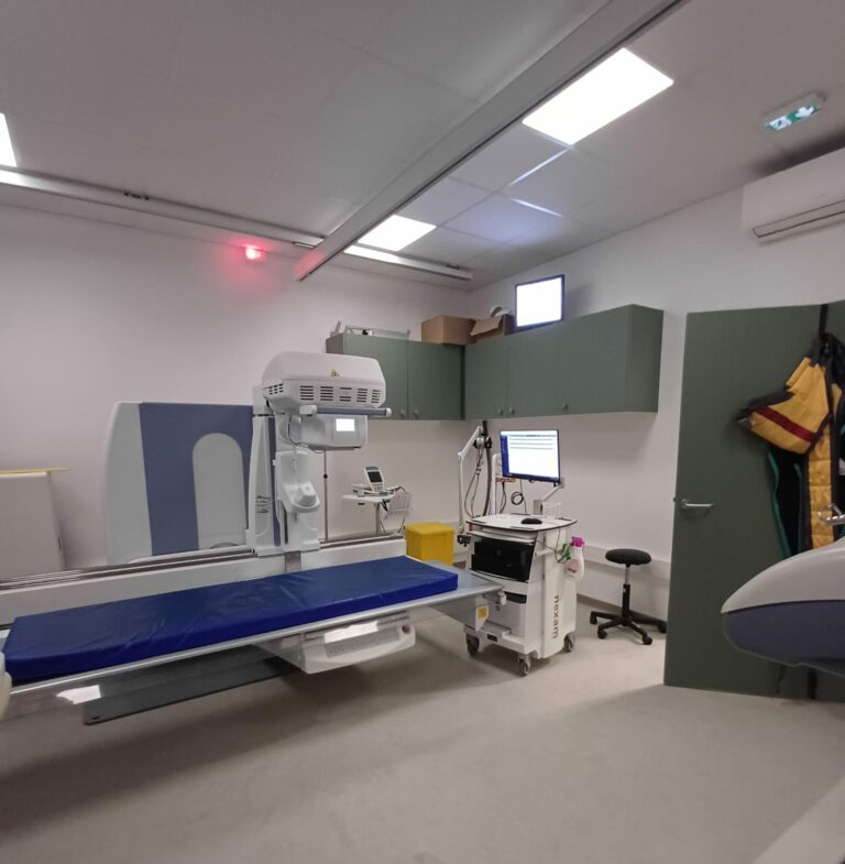 Photo de la salle de radiologie avec la table d'examen et l'appareil de radiographie au dessus